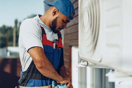 Young black man repairman checking an outside air conditioner unitの写真素材