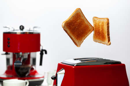 Two toasts jumping out of red toaster against white backgroundの写真素材