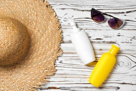 Straw hat, sunglasses and sunscreen bottle on wooden backgroundの写真素材