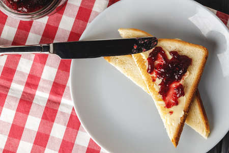 Toasted bread slices with berry jam on wooden table