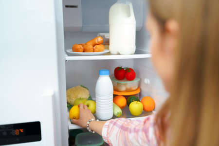 Hand of a woman taking food from the fridgeの写真素材