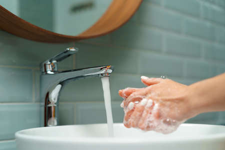 Close up of a woman washing her hands in a bathroom sinkの写真素材