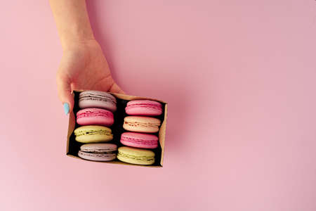 Womans hands holding box with colorful macaroon cookies