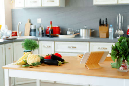 Kitchen table with frsh vegetables and digital tabletの写真素材