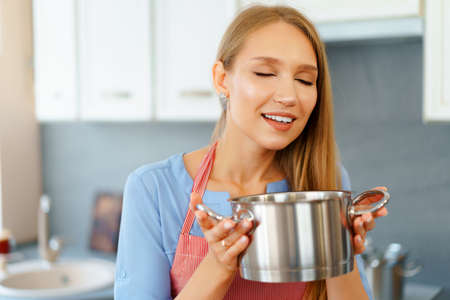 Attractive young blonde woman checking cooked foodの写真素材