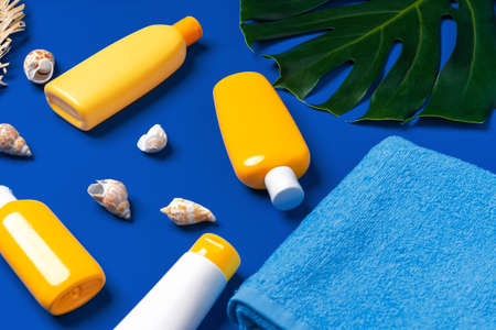 Bottles with sunblock cosmetics and seashells on dark blue backgroundの写真素材