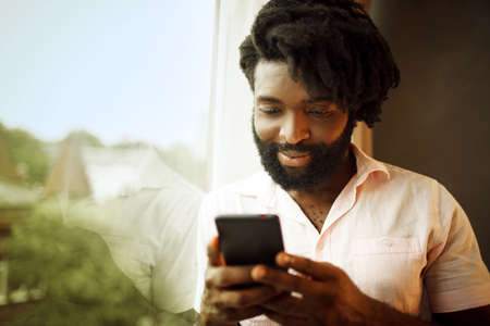 Bearded young african american man looking at his smartphoneの写真素材