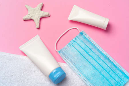 Medical mask with sunscreen cream on pink background. Coronavirus summer concept