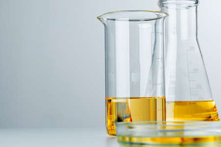 Laboratory glassware with yellow oily liquid on grey backgroundの写真素材