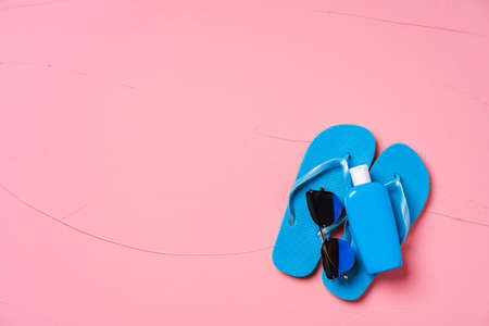 Blue flip-flops with sunscreen and sunglasses on pink backgroundの写真素材