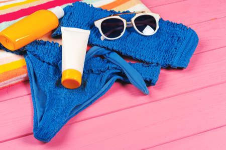 Blue bikini with sunblock cream bottle on bright pink wooden backgroundの写真素材