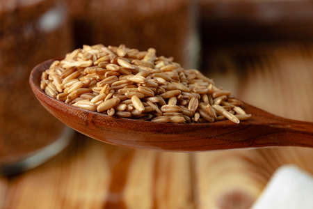 Wooden spoon with raw uncooked oats grain