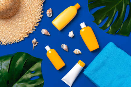 Bottles with sunblock cosmetics and seashells on dark blue backgroundの写真素材