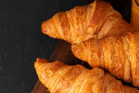 Fresh croissants on wooden board close up