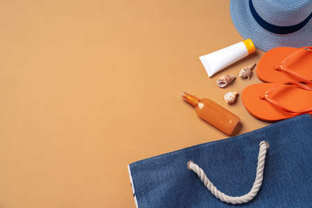 Beach bag with suntan products, flip-flops and hat on beige backgroundの写真素材