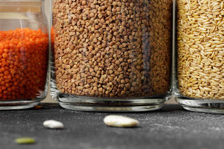 Glass jars with grains on kitchen tableの写真素材