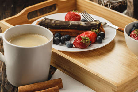 Eclair cake with chocolate glaze on wooden tray