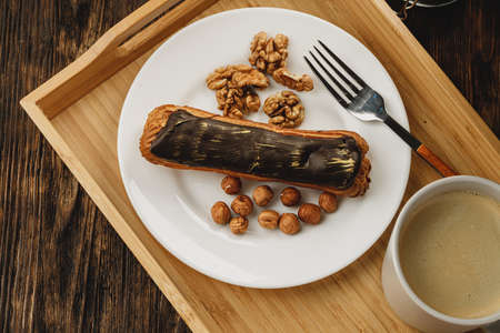 Eclair cake with chocolate glaze on wooden trayの写真素材