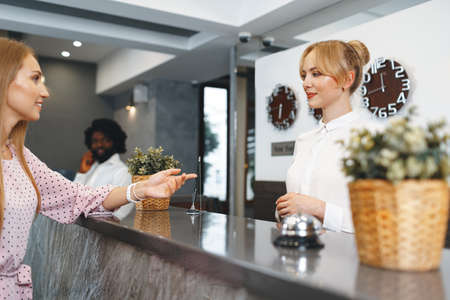 Blonde woman hotel guest checking-in at front desk in hotel