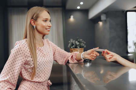 Young woman hotel guest receiving key card from receptionistの写真素材