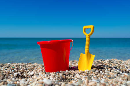 Toy bucket and spade on the beach stonesの写真素材