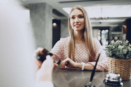 Young beautiful woman hotel guest paying for her stay with credit card at front deskの写真素材
