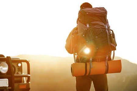 Portrait of a young traveler man in hiking equipment standing near his off-road car