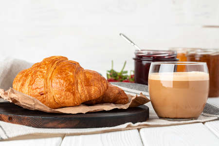 Tasty croissant with cup of coffee with milk on kitchen tableの写真素材