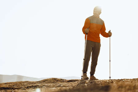 Man traveler with trekking sticks going up the mountainの写真素材