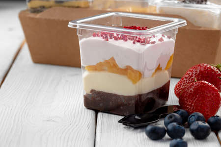 Creamy dessert in a plastic box on wooden tableの写真素材