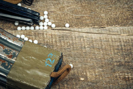 Close up of airsoft gun magazine and airsoft balls on wooden background