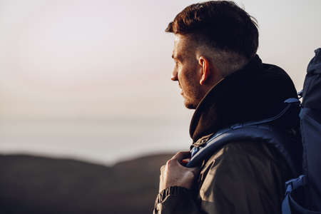 Young caucasian man traveler with big backpack hiking in the mountainsの写真素材