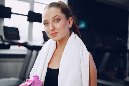 Young sporty woman having a drink in a gym after workout