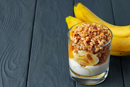 Tasty breakfast with granola, yoghurt and fruits in a glass bowlの写真素材