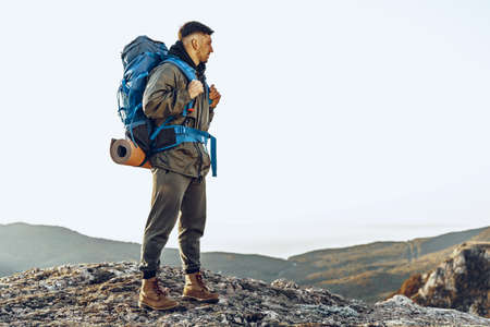 Young caucasian man traveler with big backpack hiking in the mountains
