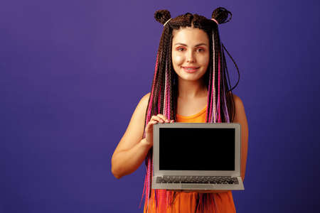 Fashionable young woman student with long afro braids holding laptop