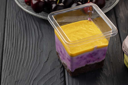 Mousse dessert in plastic transparent box on black wooden table