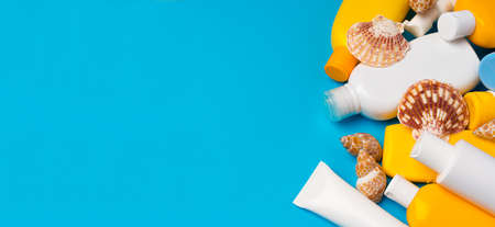 Sunscreen cream bottles with sea shells on blue background