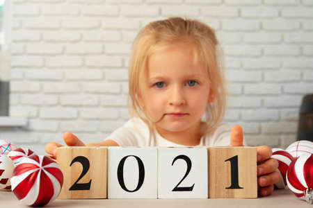 Toddler girl holding 2021 wooden cubes. Conceot of New Year 2021の写真素材