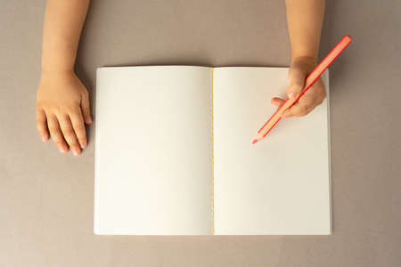 Kids hands writing in open notebook, top view, copy spaceの写真素材