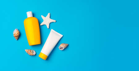 Sunscreen cream bottles with sea shells on blue backgroundの写真素材