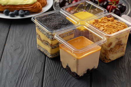 Mousse dessert in plastic transparent box on black wooden tableの写真素材