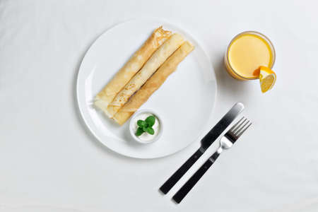 Russian pancakes served in rolls with sour cream