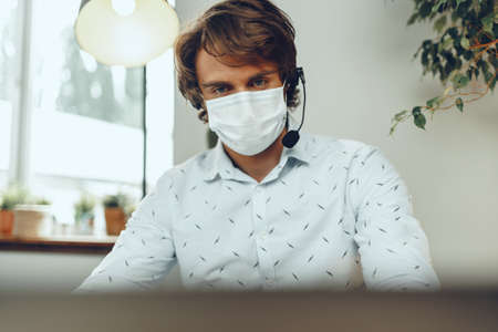 Man in medical mask working from home while coronavirus quarantine