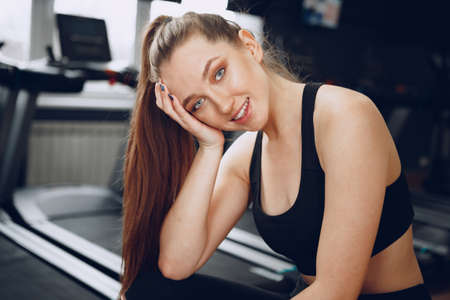 Brunette young woman sitting tired in a gym after workout
