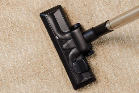 Red vacuum cleaner on a beige carpet