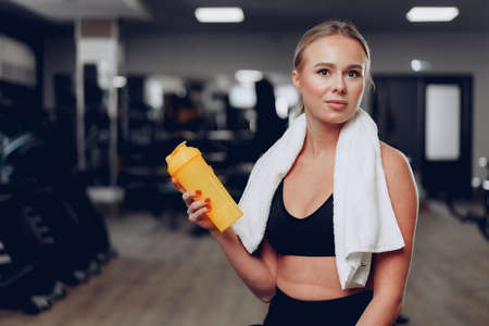 Young sporty woman having a drink in a gym after workoutの写真素材