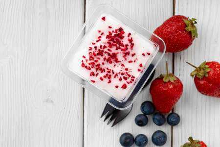Creamy dessert in a plastic box on wooden tableの写真素材