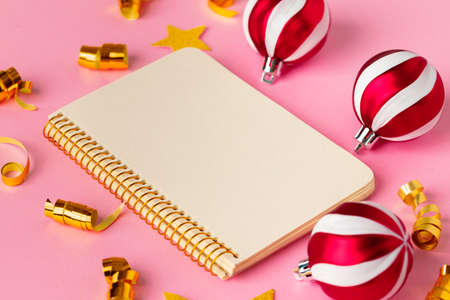 Open notepad with Christmas balls on pink backgroundの写真素材