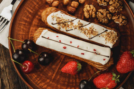 Two eclairs decorated with berries and nutsの写真素材